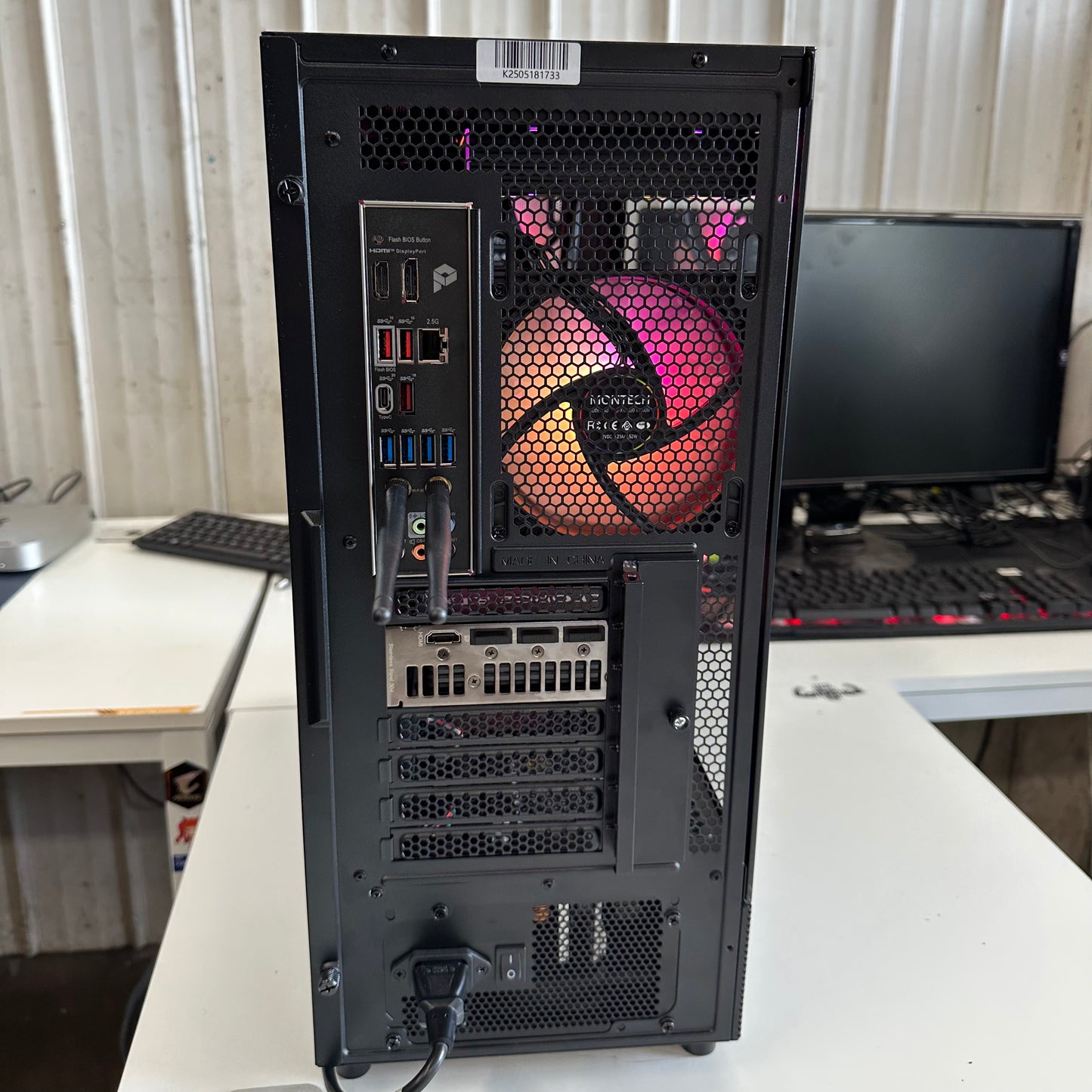 Back view of a computer tower with a colorful cooling system on a desk.