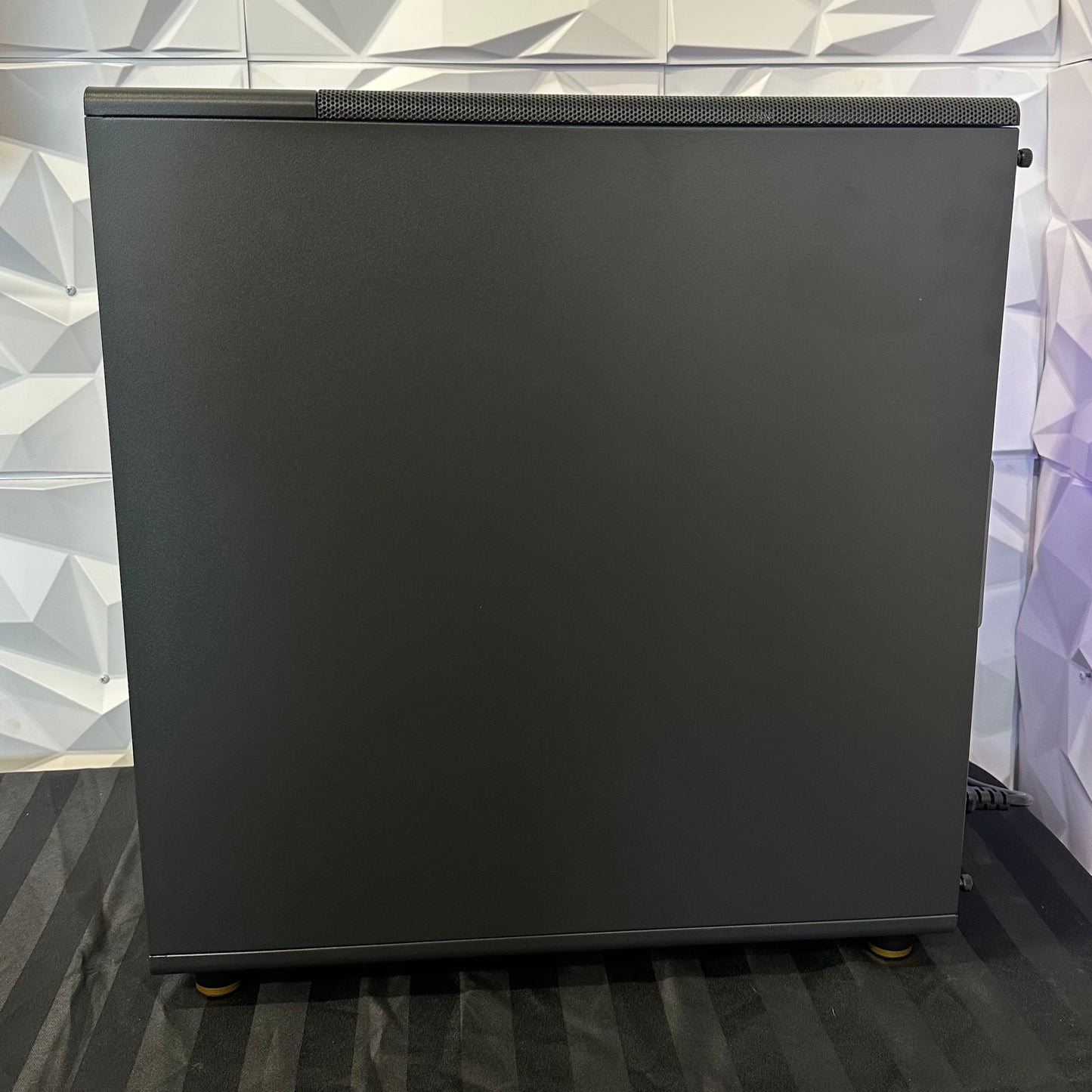 Black computer case on a reflective surface with a patterned wall in the background