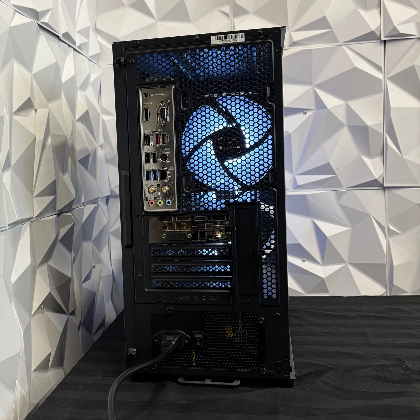 Computer tower with blue LED lighting against a geometric-patterned wall.