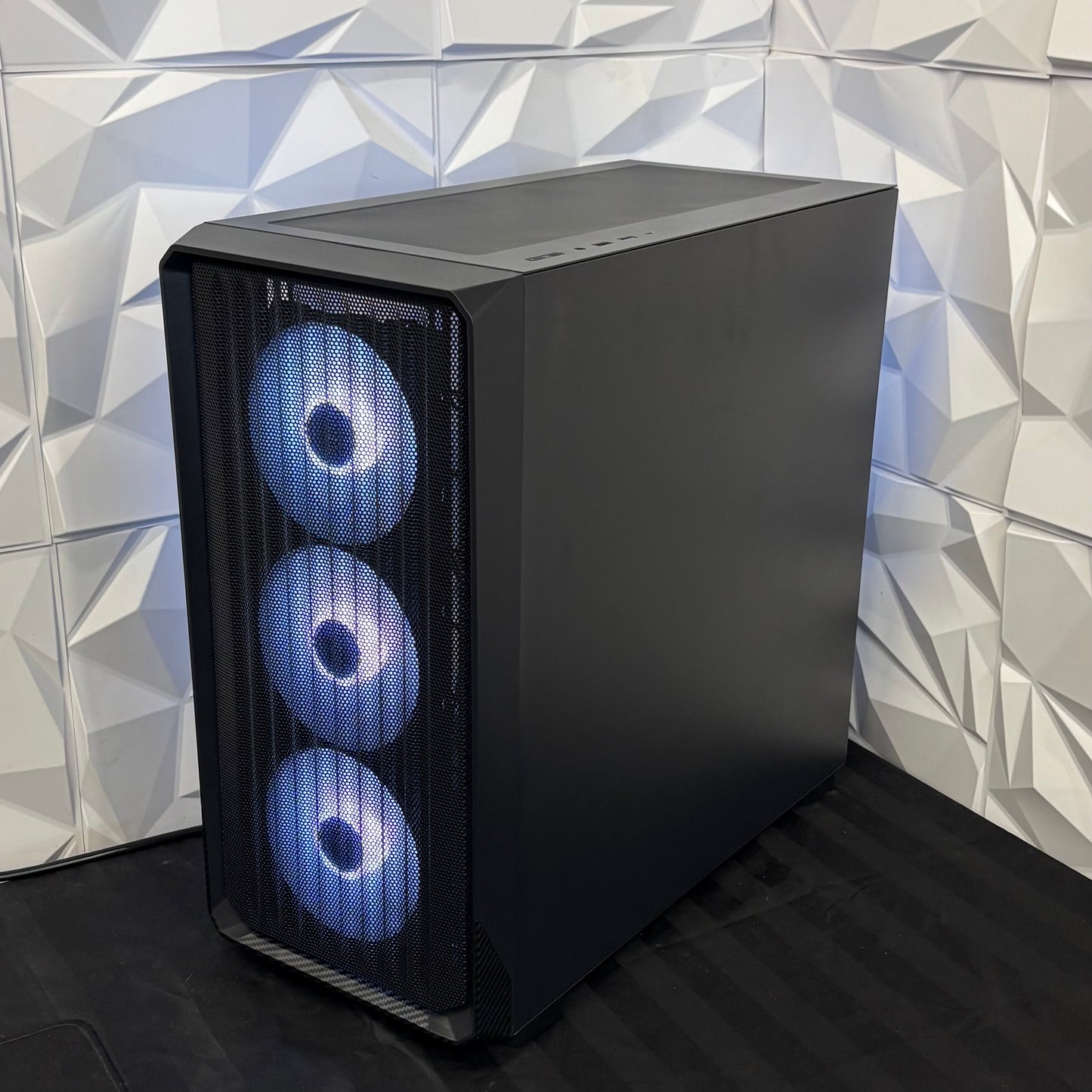 Black computer case with blue LED lights against a geometric-patterned wall.
