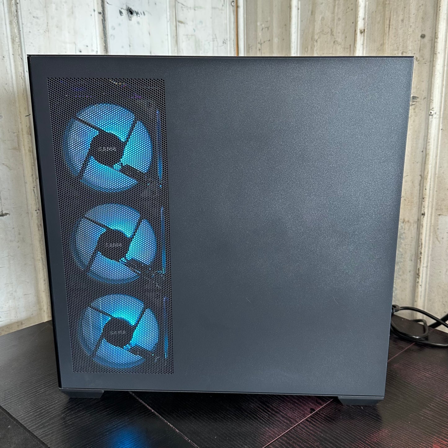 Black computer case with blue LED fans on a wooden surface