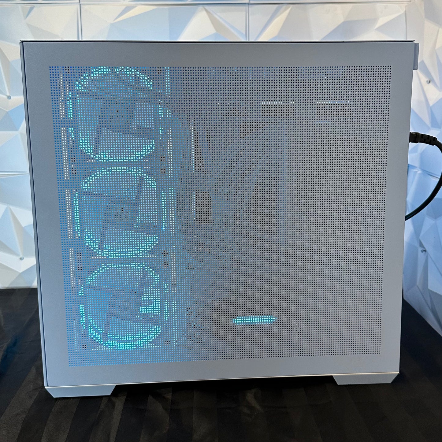 Computer case with mesh front panel and glowing text on a reflective surface