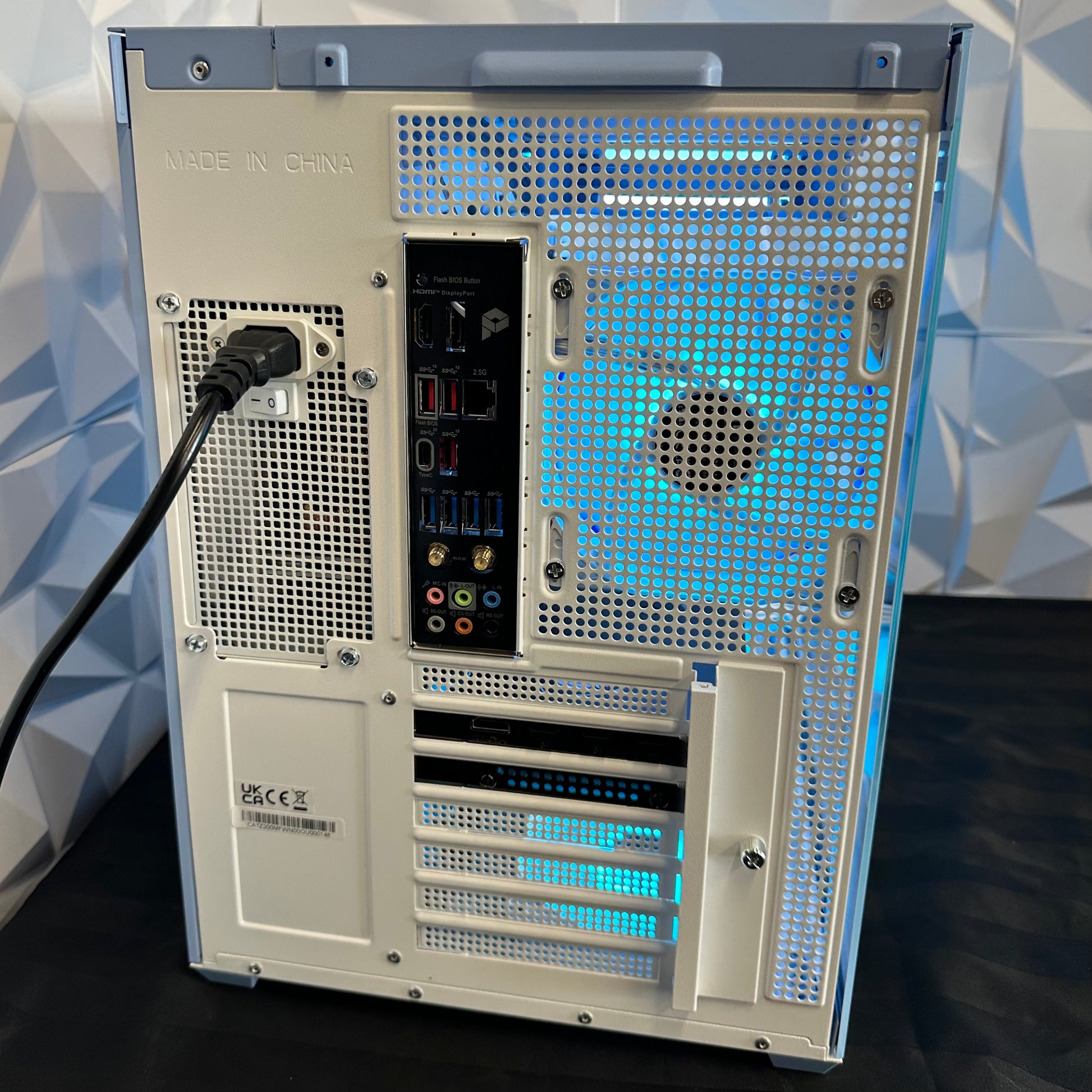 Computer case with visible cooling system and ports against a geometric patterned wall.