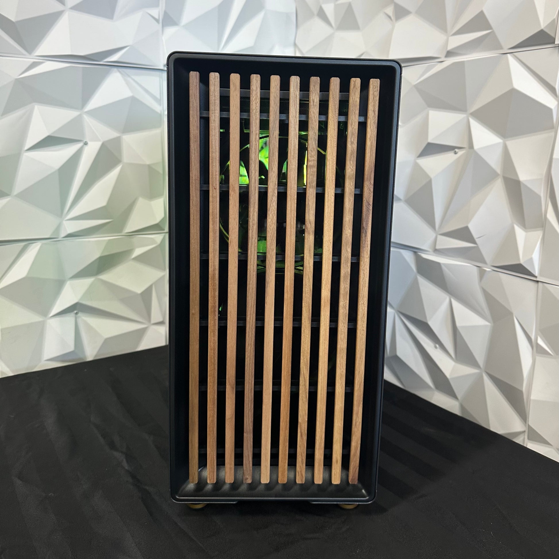 Black rectangular object with wooden slats against a geometric-patterned wall.