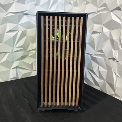 Black rectangular object with wooden slats against a geometric-patterned wall.