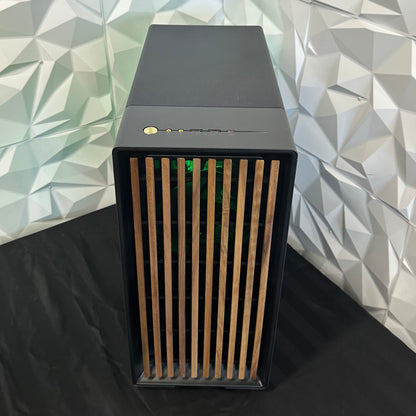 Black computer case with wooden side panel against a geometric patterned wall.