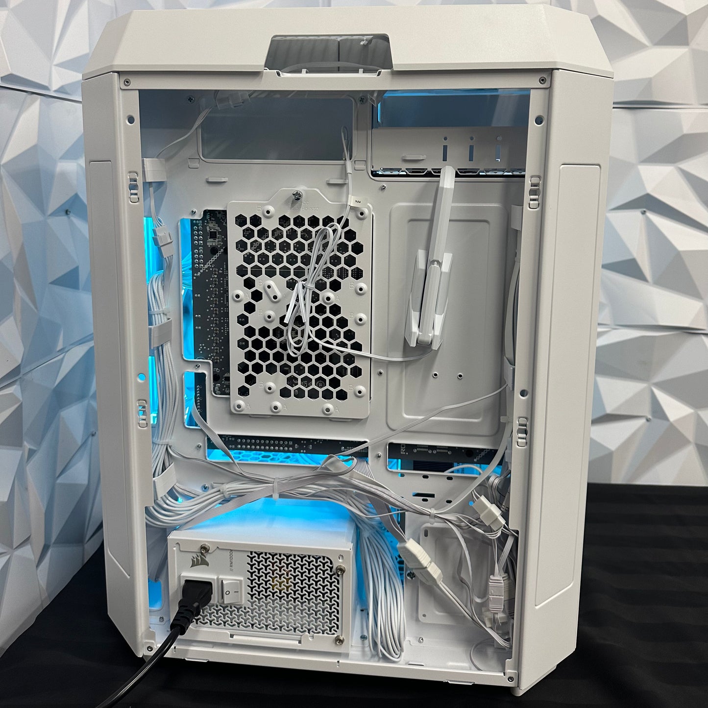 Computer case with open side panel showing internal components against a geometric patterned wall.