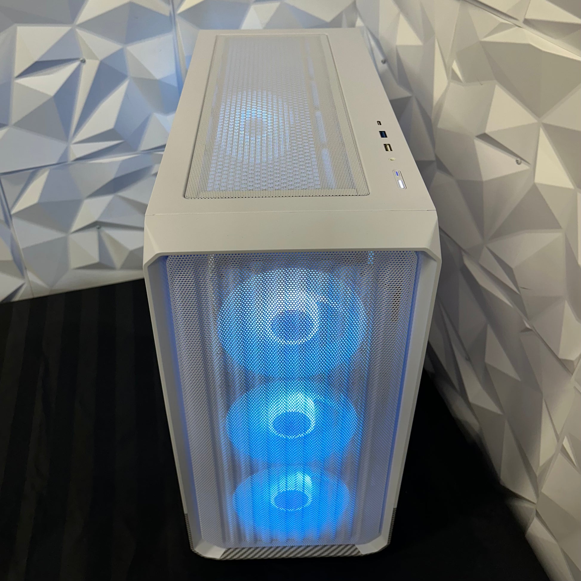 Computer case with blue LED lights against a geometric-patterned wall