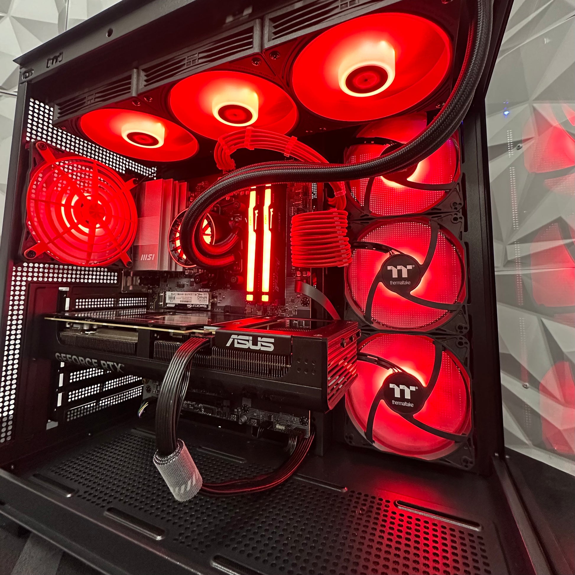 Close-up of a computer case with red LED fans and ASUS branding.
