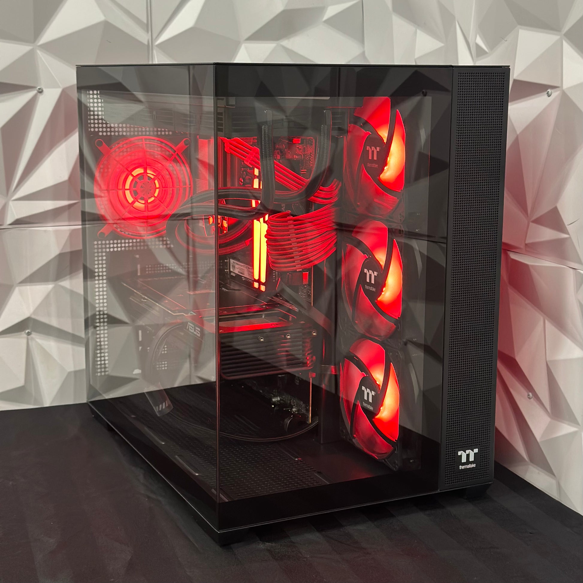 Glossy black computer case with red lighting on a geometric patterned wall background