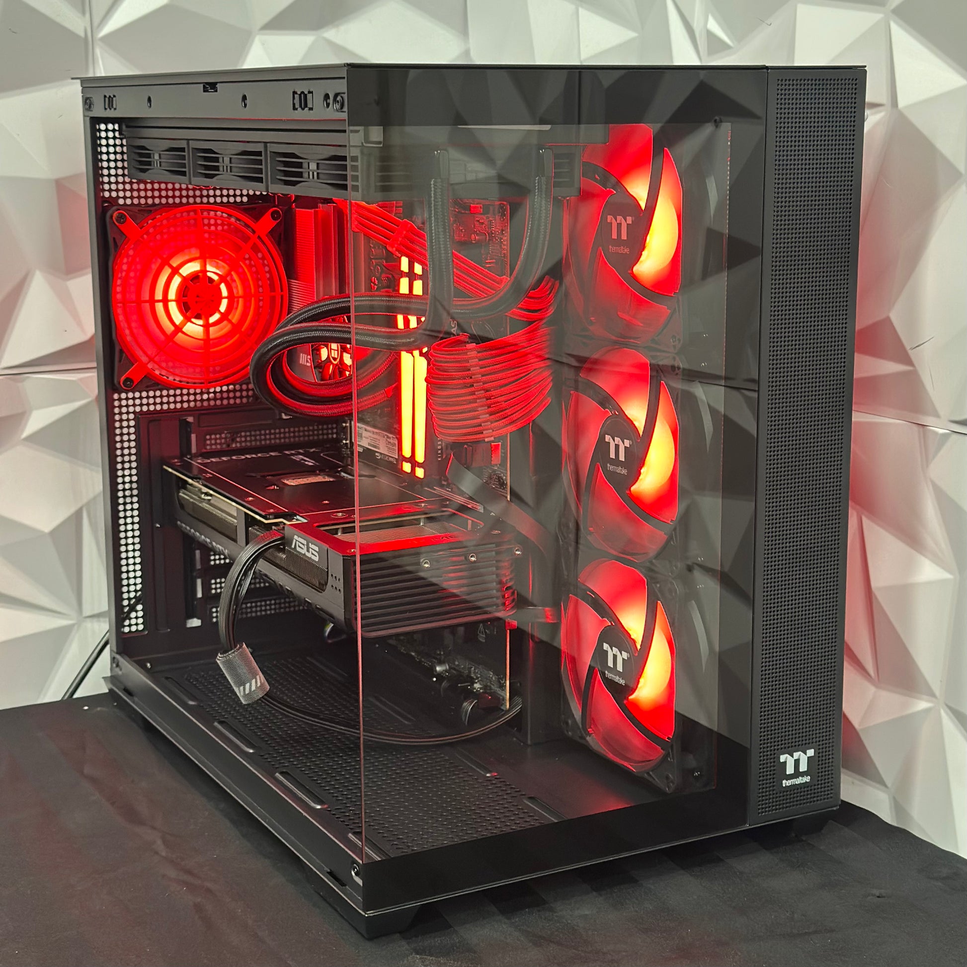 Computer case with red lighting and transparent side panel on a geometric patterned wall background