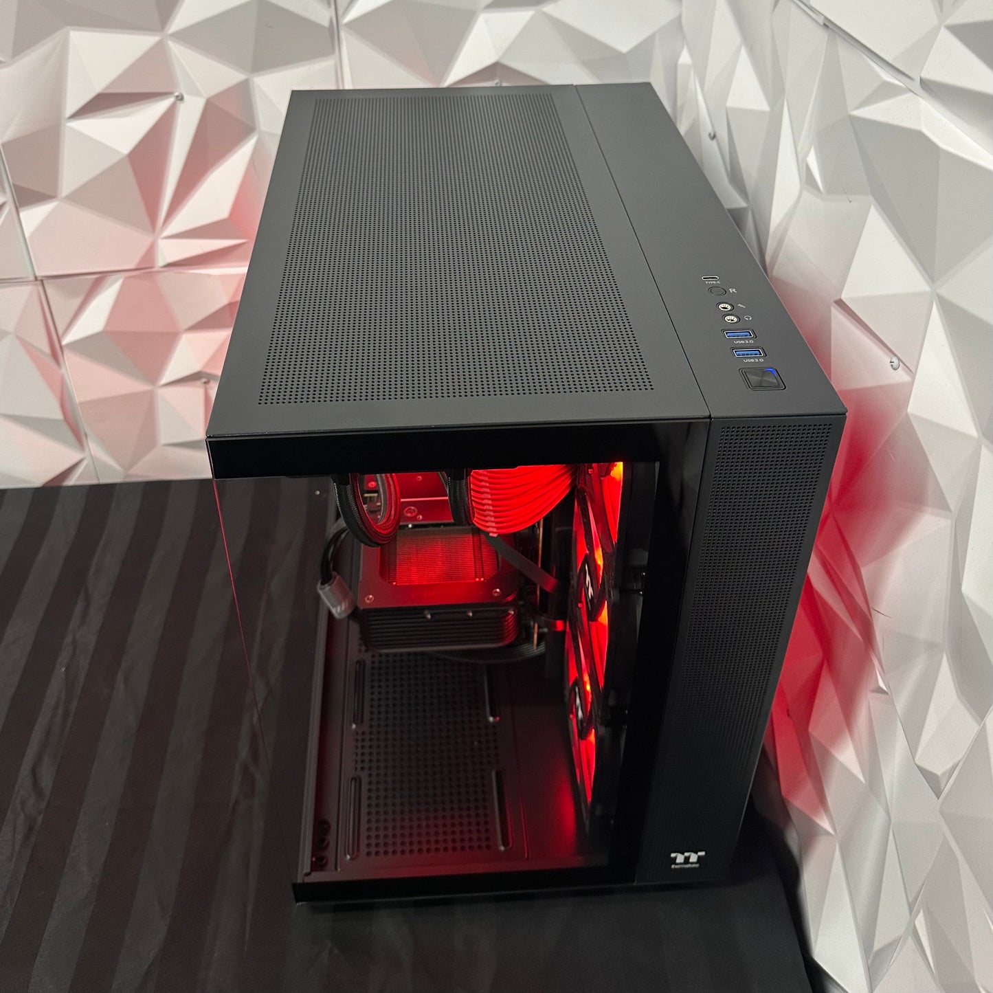 Black computer case with red interior lighting on a geometric patterned background