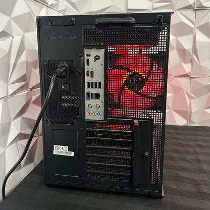 Back view of a computer case with visible components against a geometric-patterned wall.