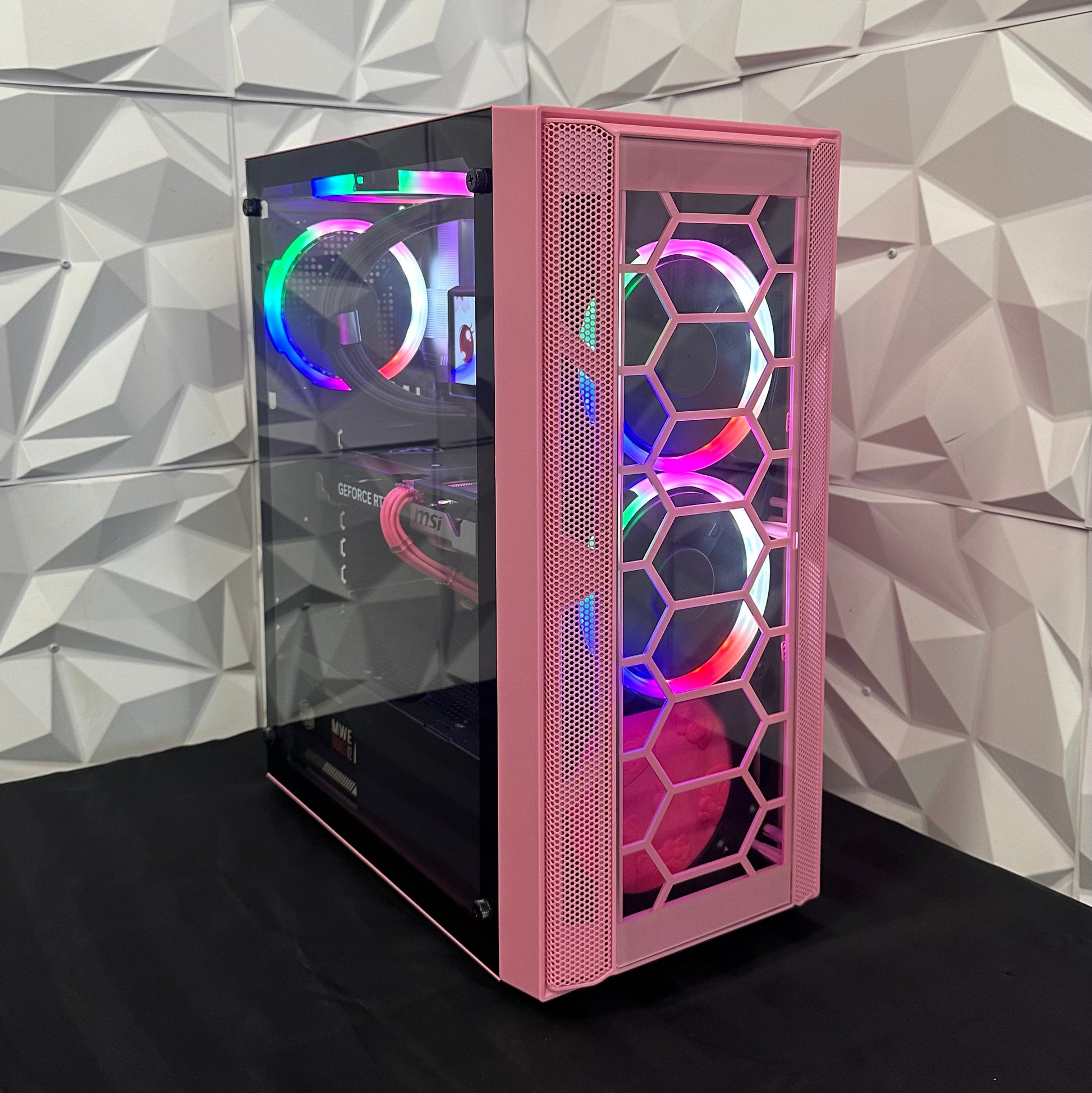 Pink computer case with RGB lighting against a geometric patterned wall