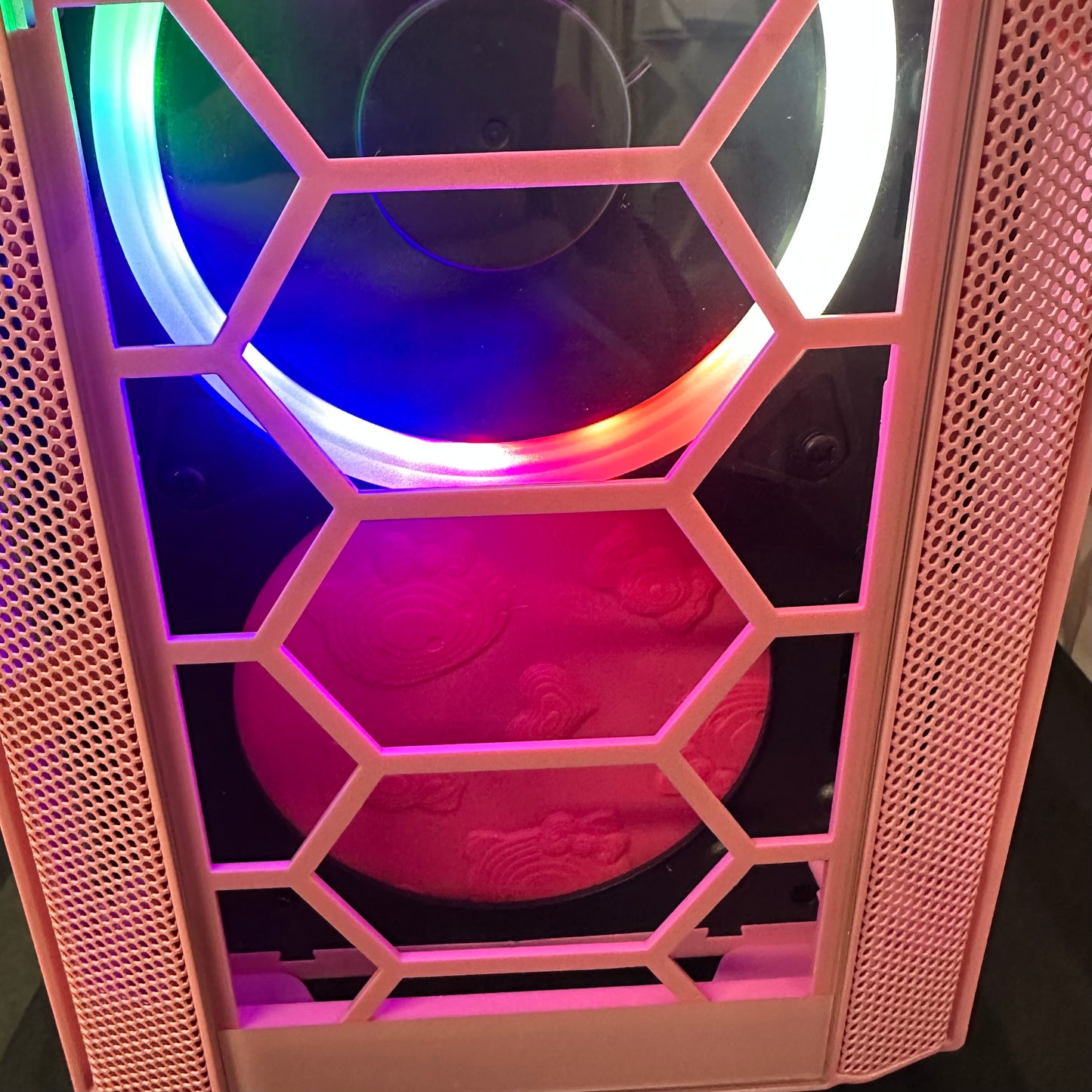 Close-up of a computer case with RGB lighting and honeycomb design.